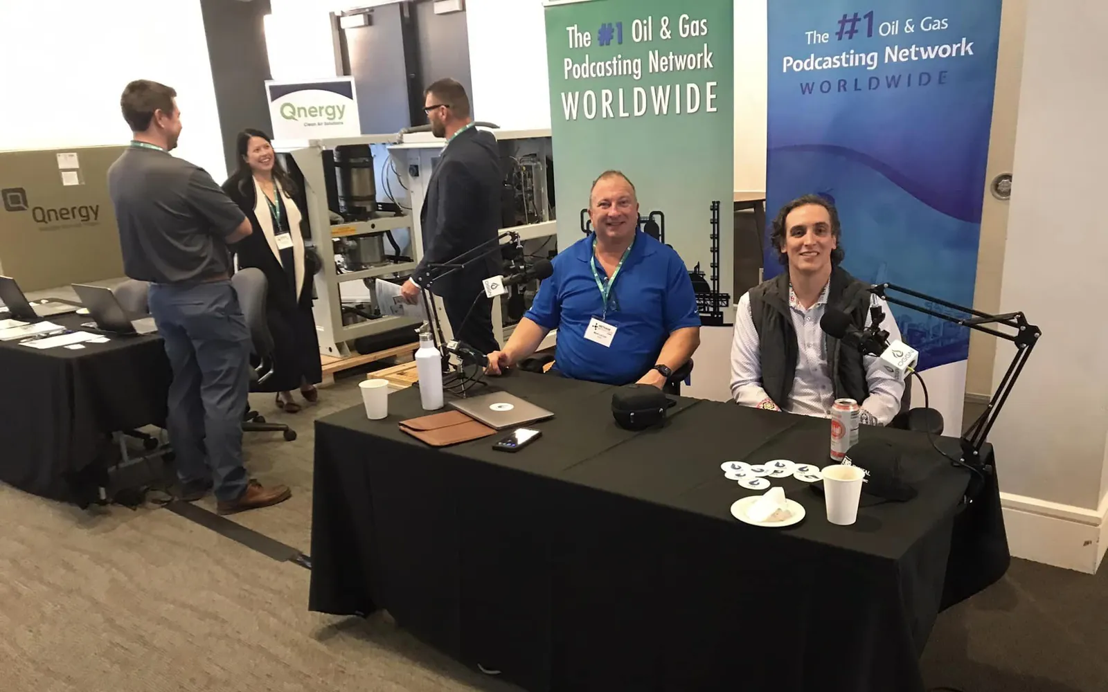Mark LaCour and Matthew Bertram seated at the OGGN podcast table with microphones, in front of Oil & Gas Global Network banners on a conference floor
