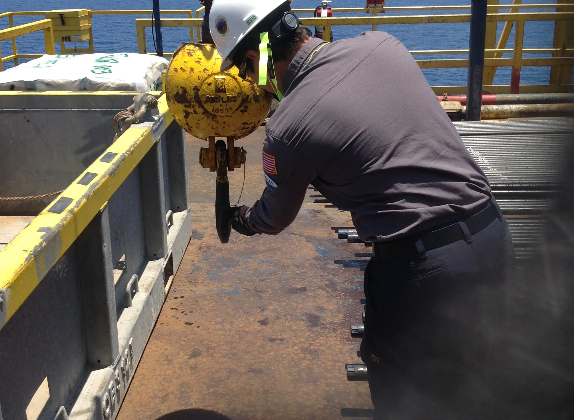 Offshore worker inspecting equipment on a platform deck.