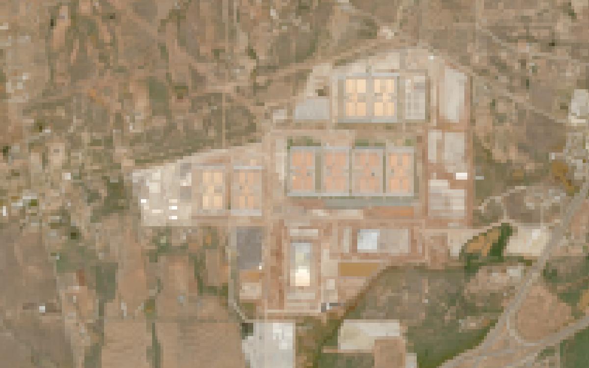 Satellite image of the same area in October 2026: a large rectangular campus of rows of data center buildings with graded pads and roads, next to the interstate.